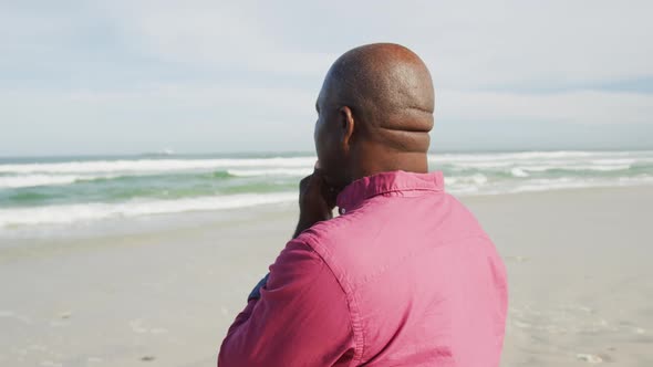 African american man walking on a beach in thought looking at the sea