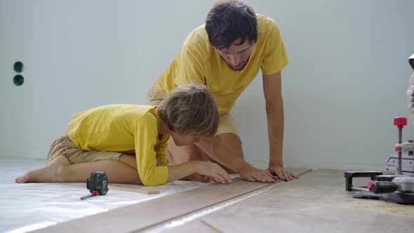 Father and His Little Son Install Laminate on the Floor in Their Apartment