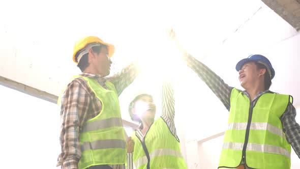 Engineer team and contractor raise their hands up together for joining hands in factory construction