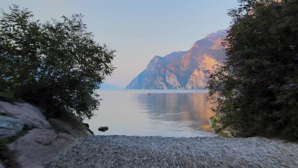 Aerial view of Riva del Garda from beach to Garda lake at sunrise. Shooting in 4k. Drone on the wate