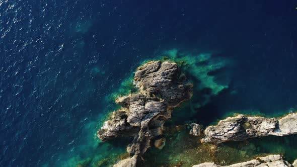 Top down view of rocks in clear blue sea.