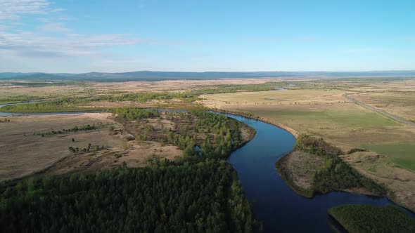 Aerial View of a River Flowing Through Rural Area with Meadows Rare Trees and with the Road on the