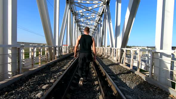 Male Athlete Walking on Rails. Back View Tracking Shot of Unrecognizable Sportsman Walking Along