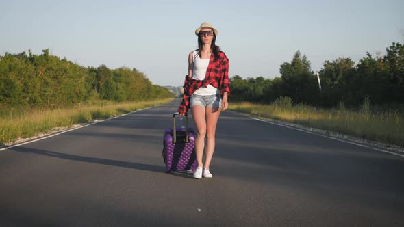 Young Woman with a Suitcase on Road. Funny Beautiful Girl Traveler. Travel Concept Video.