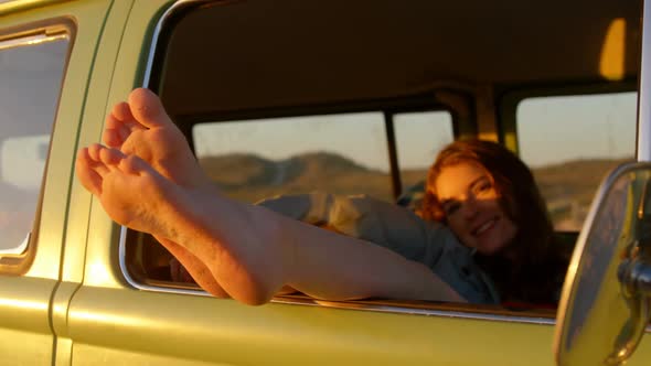 Woman legs out of the van window during sunset 4k