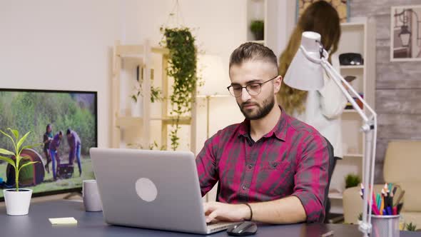 Handsome Man Laughing While Working on Laptop in Living Room