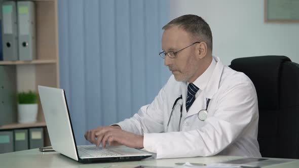 Tired Therapist Filling in Electronic Record Files After Patient Examination