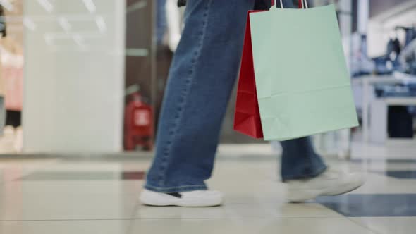 Woman Holds Shopping Bags Walking Across Mall Closeup