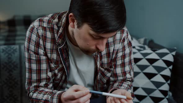 A Worried Man Looks at a Pregnancy Test at Home