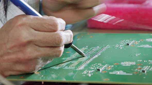 Manual soldering of electronic components on a PCB board, close up