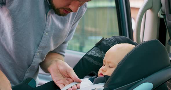 Camera Inside the Car Closeup Baby Boy Sits in the Baby Car Seat Inside of Car Young Bearded Father