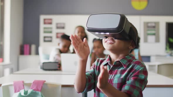 Video of happy african american boy wearing vr headset in classroom