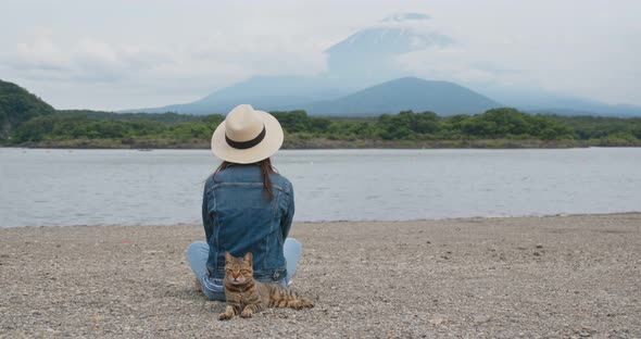 Woman sit at the lake side with a wild cat in shojiko of Japan