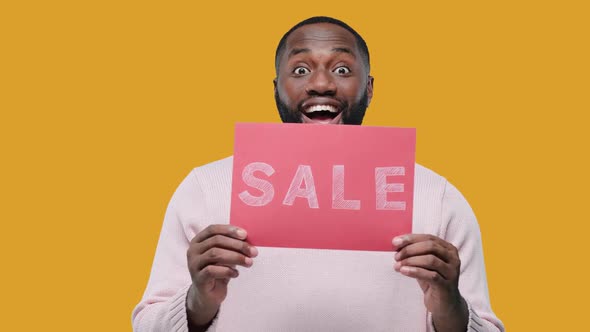 Amazed Young Black Man Guy in Casual Hold Banner with SALE Title on Yellow Background