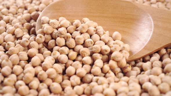 Wooden spoon in heaps of uncooked dry chickpeas.