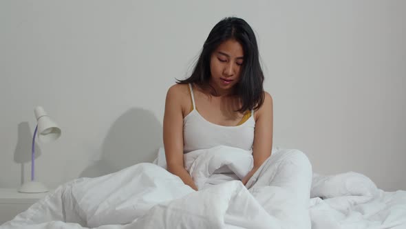 Asian young woman shocked as he wake up late for an appointment on bed in bedroom at home.