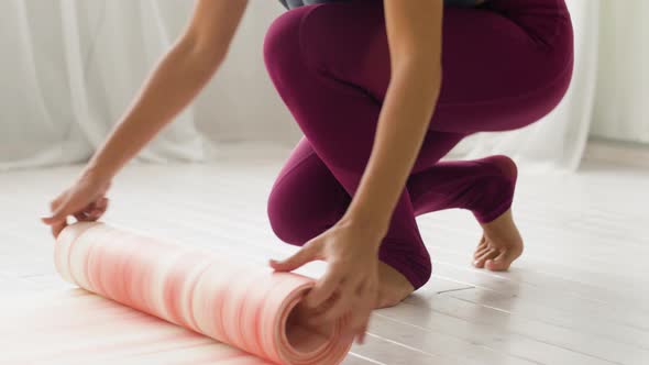 Woman Rolling Up Mat at Yoga Studio or Gym