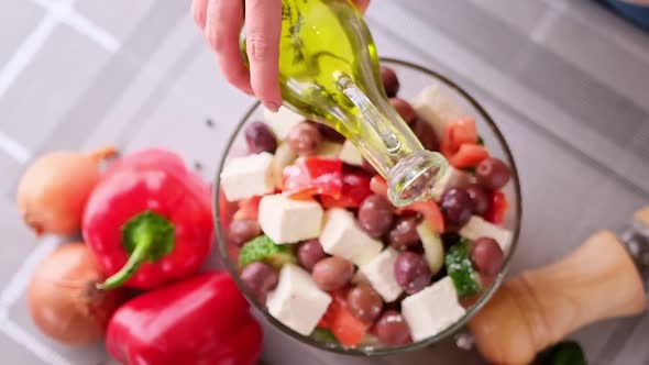 Greek Salad Preparation Series Concept  Woman Pouring Olive Oil Into Bowl with Chopped Vegetables