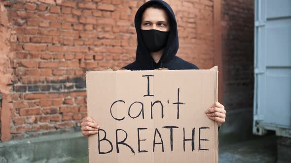 Man in Mask Stands with Cardboard Poster in Hands  I CANT BREATHE