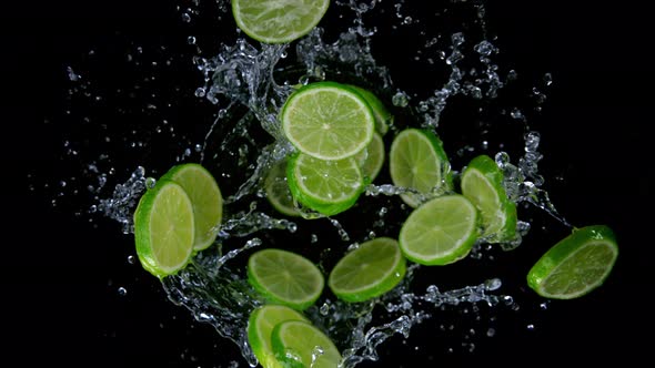 Super Slow Motion Shot of Rotating Exploded Lime Slices with Splashing Water on Black at 1000Fps