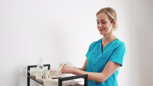 Female Caucasian Hygienist or Nurse Preparing for Medical Procedure By Putting on White Protective