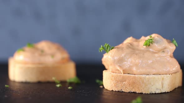 Spreading chopped parsley over tuna paste on toast