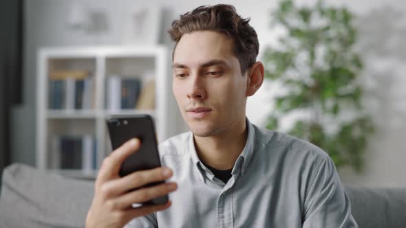 Handsome Relaxing on Couch with Smartphone