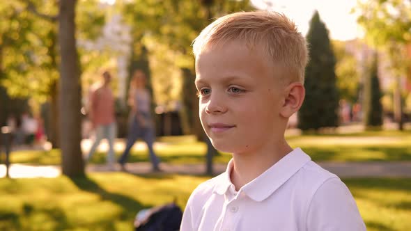 Closeup of a Little Boy Putting on Sunglasses in the Park