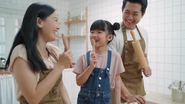 Asian happy family spend time together, singing and dancing while bake bakery in kitchen at home.