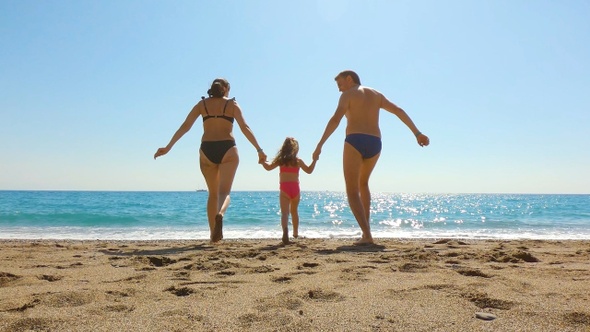 Happy family run on sand into the sea