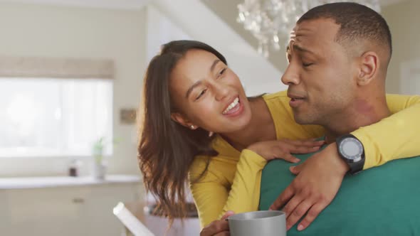 Happy biracial couple with coffee talking and embracing