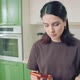 Young Woman in Tshirt Making a Cell Phone Call While Cooking at Home Kitchen - VideoHive Item for Sale