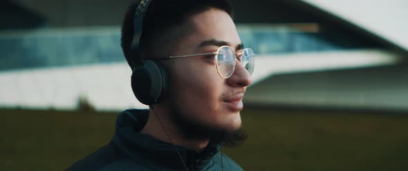 Young man with glasses listening to music holding and slightly nodding his head