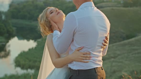 Wedding Couple Having Fun at Sunset on a Rock Near the River