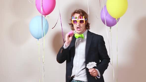 Young man blowing party horn and dancing