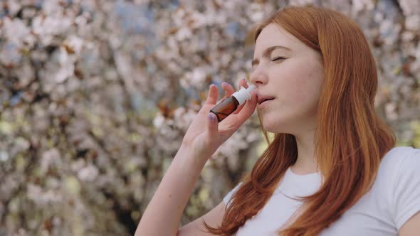 Sick Young Lady Using Nasal Spray in Cherry Tree Garden