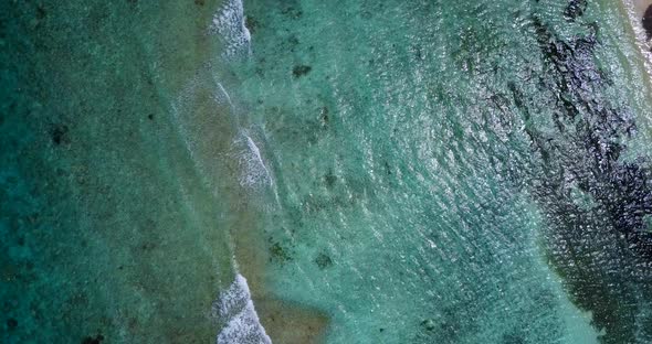 Tropical overhead travel shot of a sunshine white sandy paradise beach and aqua blue water backgroun