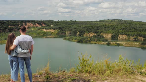 Couple Is Standing on a Mountain Cliff By the Lake. 