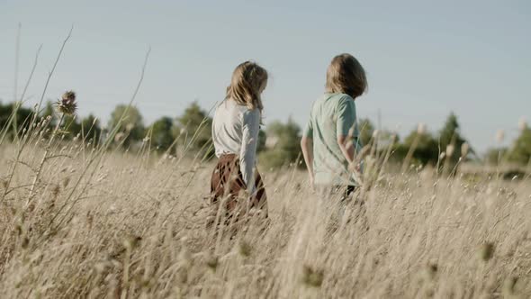 Back View of Boy and Girl Going Through Open Field