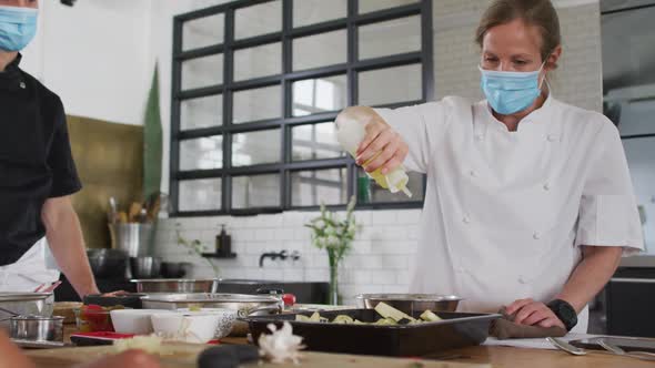 Caucasian female chef teaching diverse group wearing face masks