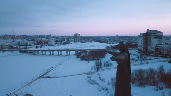 The Monument Of The Patron Mother In Cheboksary, Against The Background Of The City