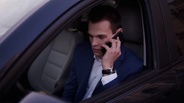 Closeup of a Man Sitting in the Car on a Driver's Seat Holding a Smartphone