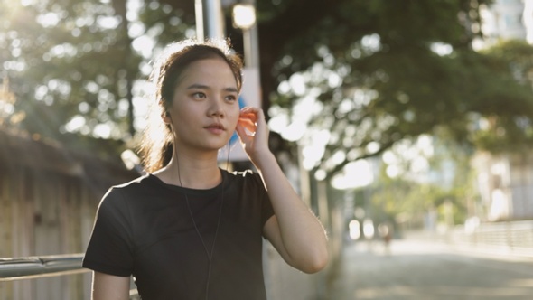 Asian woman jogging exercising running listening to music.