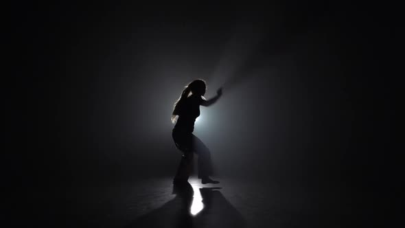 Lady Practicing Capoeira in Darkness Against Spotlight in Studio. Slow Motion.