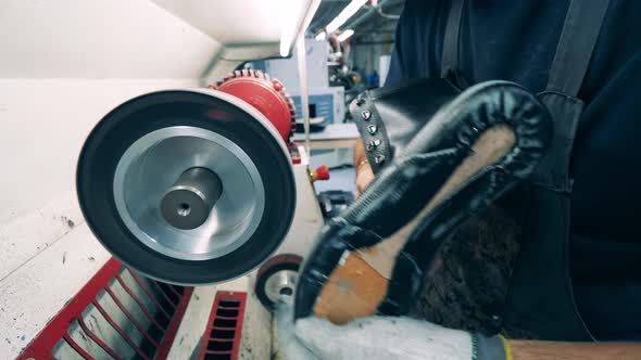 A Worker Is Using a Buffing Machine To Polish Shoes