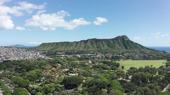 Wide rising aerial shot of the Diamond Head volcanic formation from Waikiki Beach on the island of O