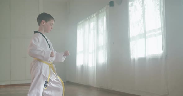 Slow motion footage of a young boy practicing martial arts inside a dojo