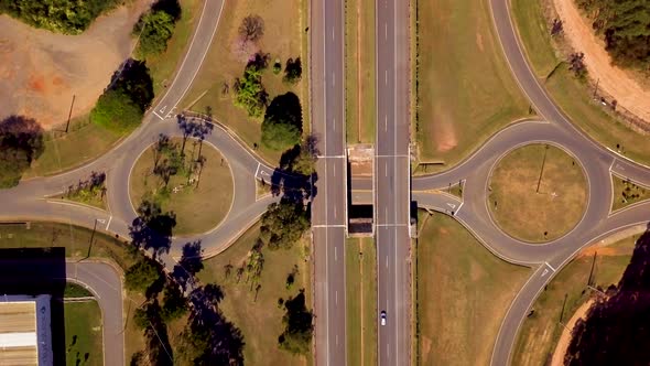 Aerial of highway interchange with roundabouts. Red car drives left to right