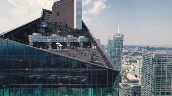 Ascending Drone Shot of the Top of Modern Glasscovered Skyscraper Looking Over the Center of Warsaw