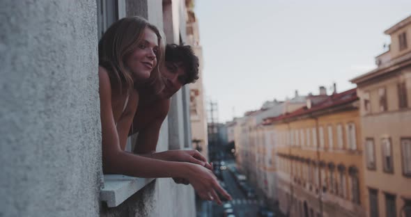 A couple speaking and looking at something from the window